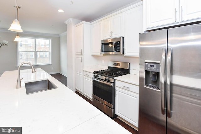 kitchen with pendant lighting, sink, appliances with stainless steel finishes, ornamental molding, and white cabinets