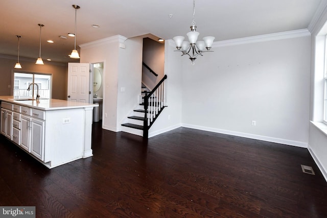 kitchen featuring pendant lighting, sink, crown molding, and an island with sink