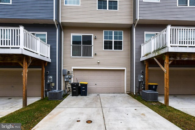 rear view of property with a garage and central AC unit