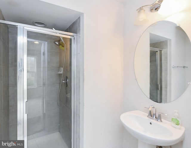 bathroom with a shower with shower door and sink