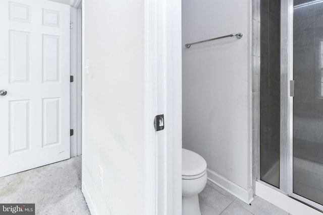 bathroom with tile patterned floors, toilet, and a shower with shower door