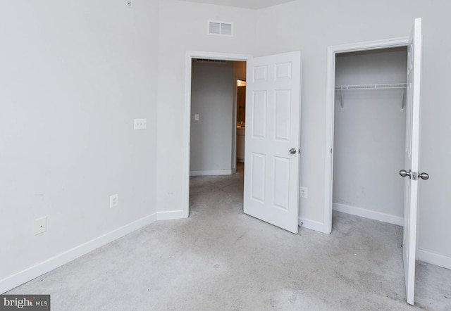 unfurnished bedroom with light colored carpet and a closet