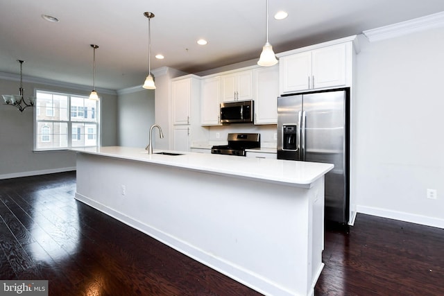 kitchen featuring pendant lighting, ornamental molding, appliances with stainless steel finishes, and a large island with sink