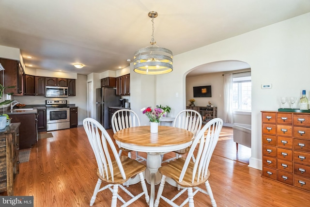 dining room featuring sink, a notable chandelier, and light hardwood / wood-style flooring