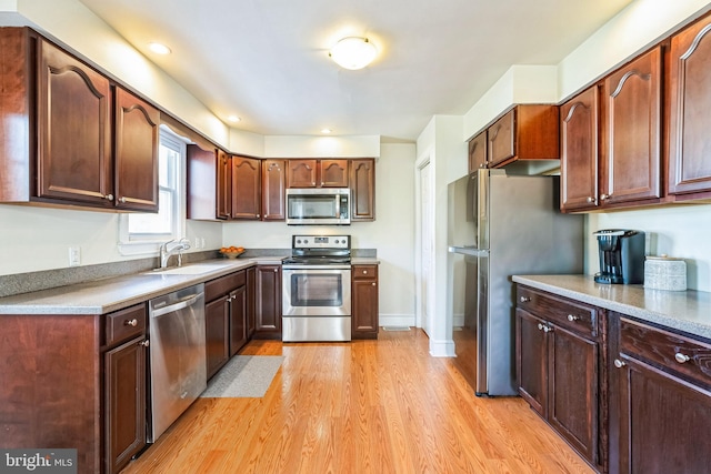 kitchen with sink, stainless steel appliances, and light hardwood / wood-style floors