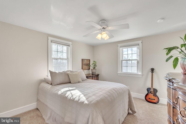 bedroom with multiple windows, light colored carpet, and ceiling fan