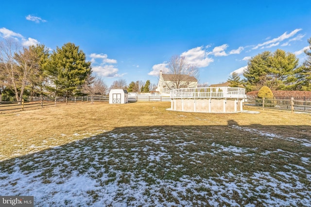 view of yard with a rural view, a fenced in pool, and a shed