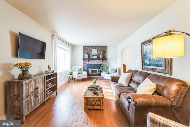 living room with a brick fireplace and wood-type flooring