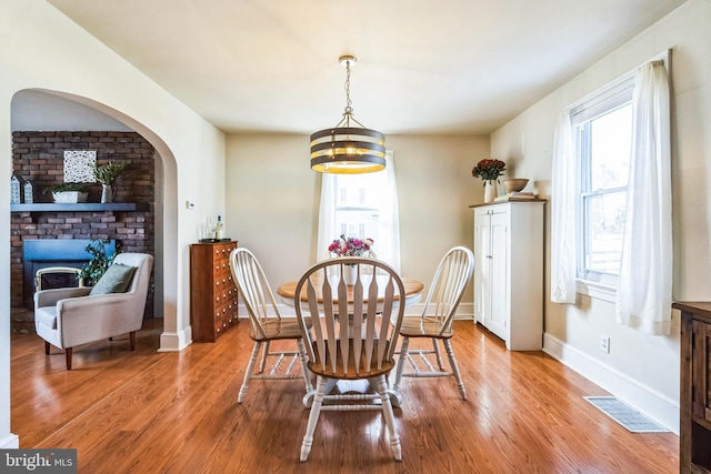 dining room featuring hardwood / wood-style floors, a notable chandelier, and a fireplace