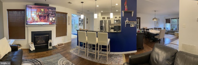 interior space featuring stainless steel appliances, dark wood-type flooring, a glass covered fireplace, and visible vents