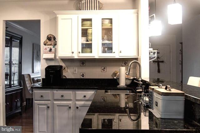 kitchen with a sink, white cabinets, ornamental molding, decorative backsplash, and glass insert cabinets