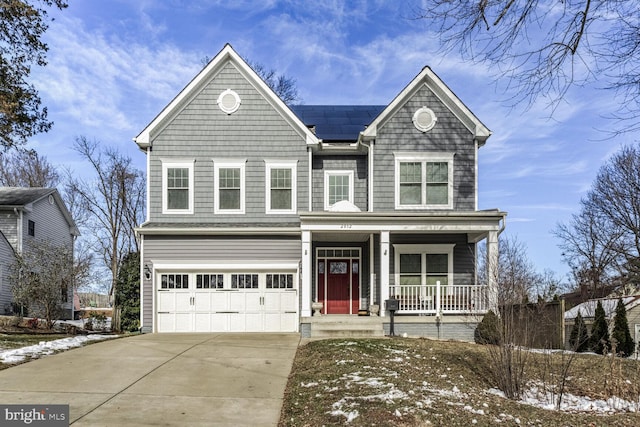 traditional home with solar panels, a garage, covered porch, and driveway