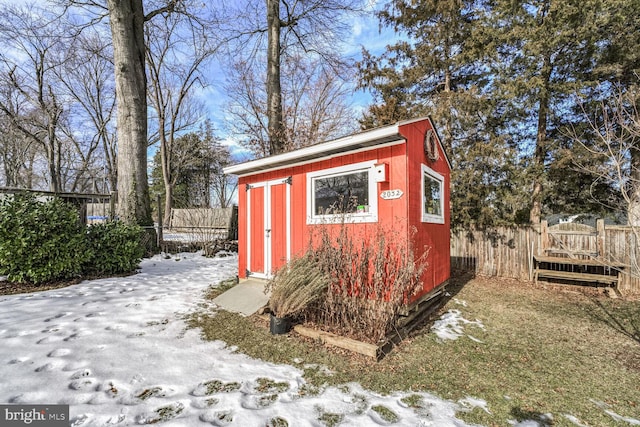 snow covered structure with an outbuilding and fence