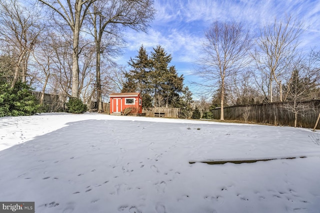 yard layered in snow featuring an outbuilding and fence