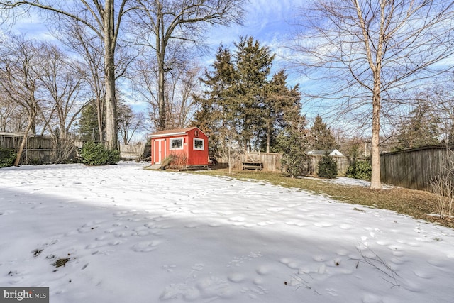 yard covered in snow featuring an outbuilding, a fenced backyard, and a storage shed