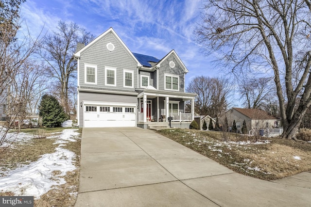 traditional-style house with an attached garage, a porch, solar panels, and driveway