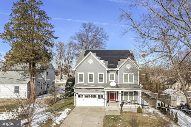 traditional home featuring roof mounted solar panels, covered porch, concrete driveway, and an attached garage