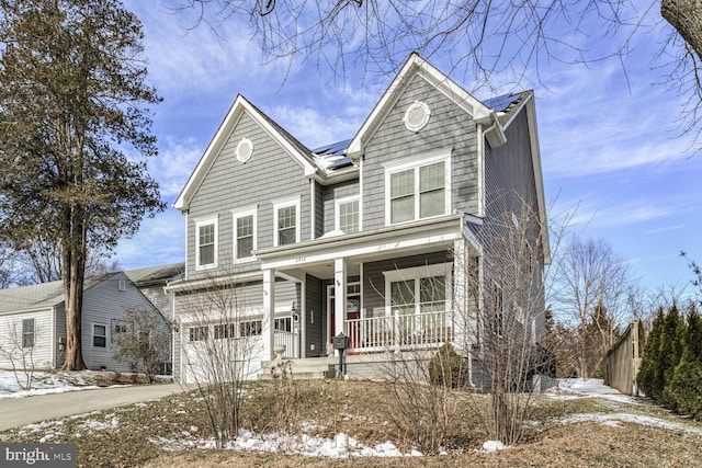 traditional home featuring an attached garage, a porch, and driveway