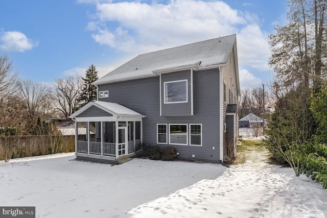 snow covered property featuring fence and a sunroom