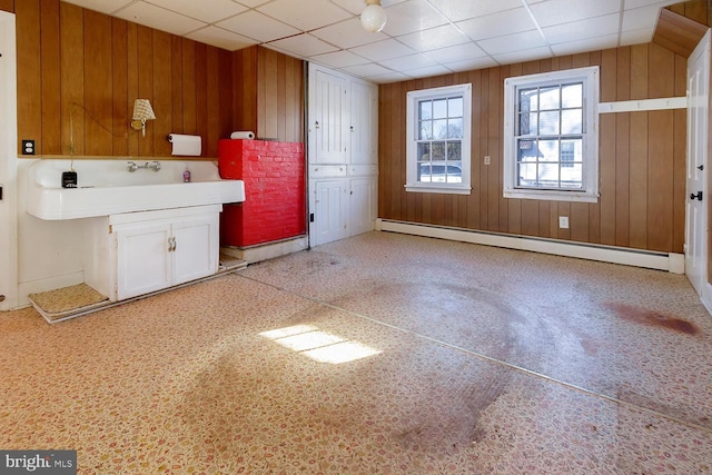 kitchen featuring baseboard heating, wooden walls, and a drop ceiling