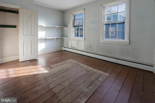 unfurnished room with hardwood / wood-style flooring and baseboard heating