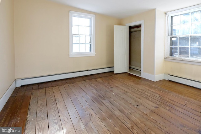 unfurnished bedroom with light hardwood / wood-style flooring and a baseboard heating unit