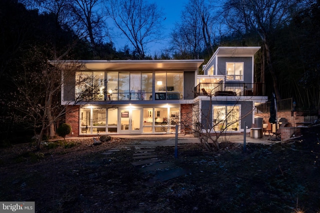 back house at twilight featuring a patio