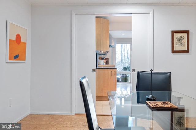 dining space with crown molding and light wood-type flooring