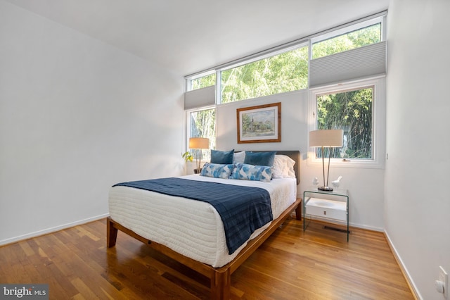 bedroom with wood-type flooring and multiple windows