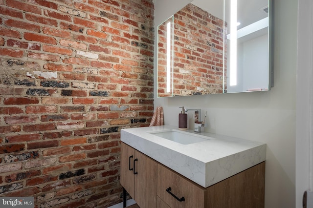 bathroom with vanity and brick wall