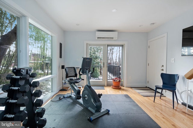 workout room with an AC wall unit, plenty of natural light, hardwood / wood-style floors, and french doors