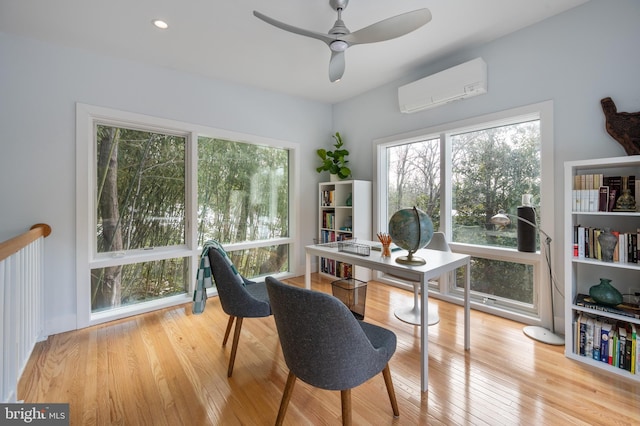 office space with ceiling fan, light hardwood / wood-style flooring, and a wall mounted AC