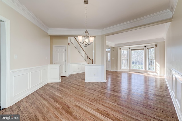 unfurnished dining area with crown molding, light hardwood / wood-style flooring, and a notable chandelier