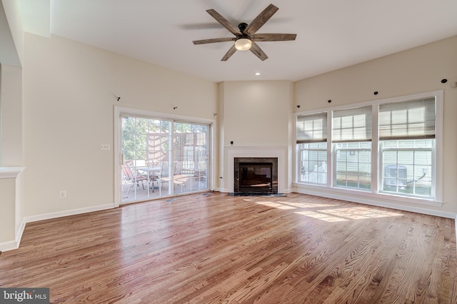 unfurnished living room with ceiling fan, a high end fireplace, and light wood-type flooring