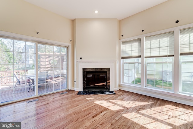 unfurnished living room featuring a healthy amount of sunlight, a fireplace, and light hardwood / wood-style floors