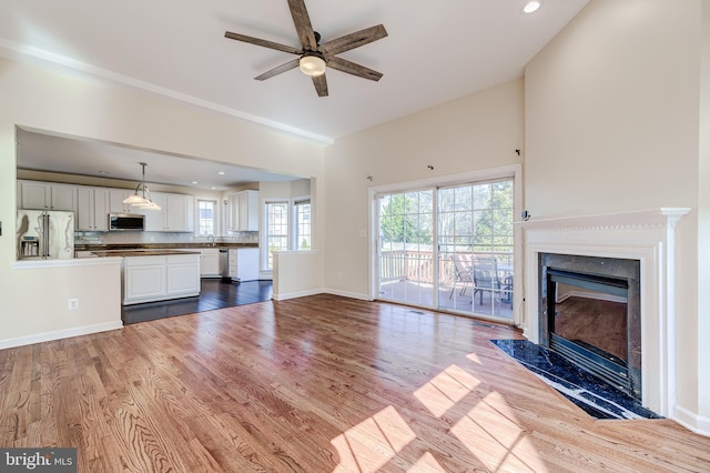 unfurnished living room featuring ceiling fan, a fireplace, and light hardwood / wood-style floors