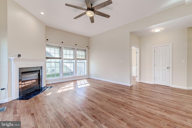 unfurnished living room with ceiling fan, a high end fireplace, and light wood-type flooring