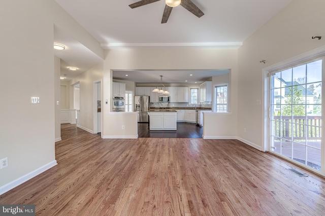 unfurnished living room featuring ceiling fan with notable chandelier, sink, and hardwood / wood-style floors