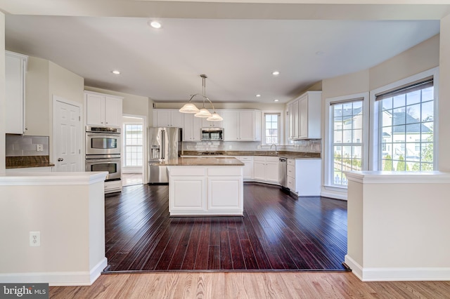 kitchen with white cabinetry, pendant lighting, stainless steel appliances, and a center island