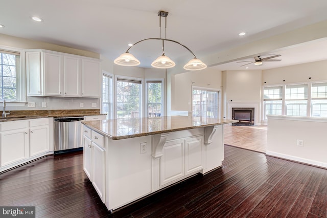 kitchen featuring a kitchen island, sink, white cabinets, hanging light fixtures, and stainless steel dishwasher