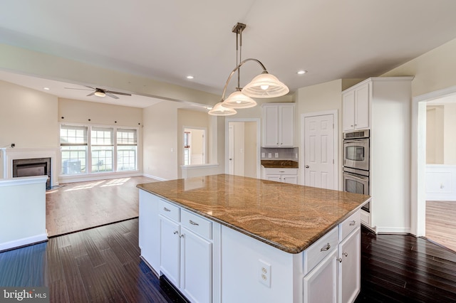 kitchen featuring pendant lighting, white cabinetry, dark stone countertops, a center island, and stainless steel double oven