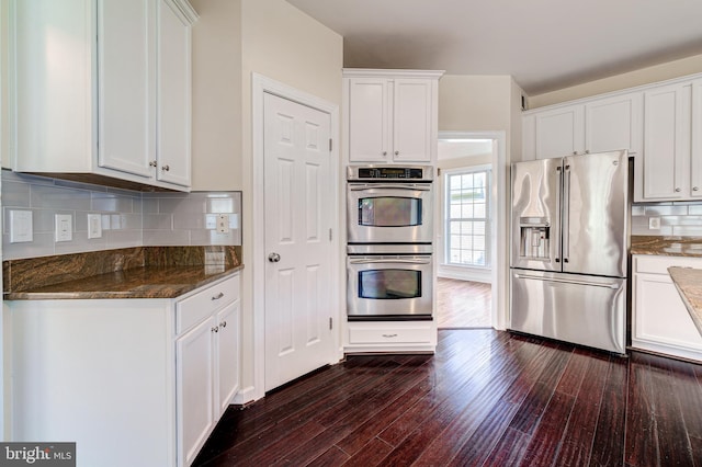 kitchen with appliances with stainless steel finishes, dark stone countertops, and white cabinets