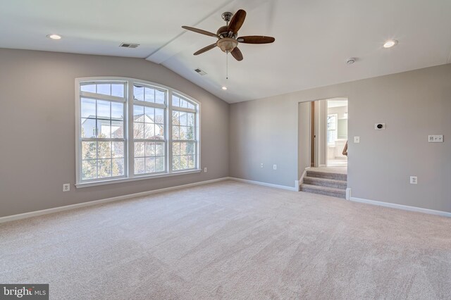 spare room featuring ceiling fan, light colored carpet, and vaulted ceiling