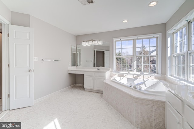 bathroom with tile patterned flooring, vanity, and tiled bath