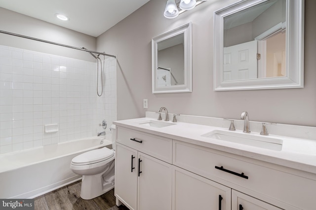 full bathroom featuring vanity, hardwood / wood-style floors, tiled shower / bath combo, and toilet