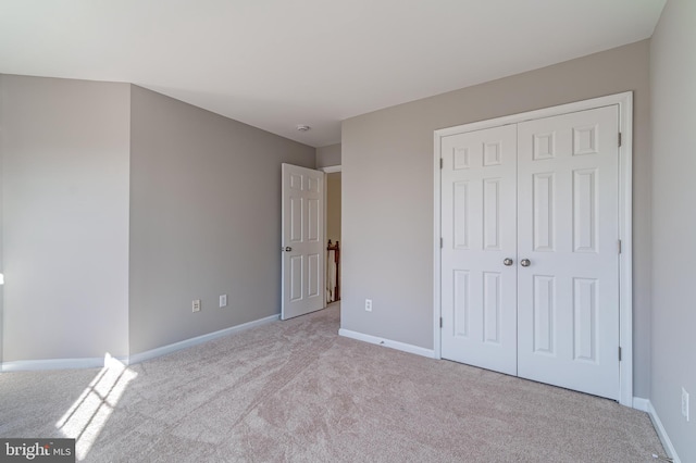 unfurnished bedroom featuring light carpet and a closet