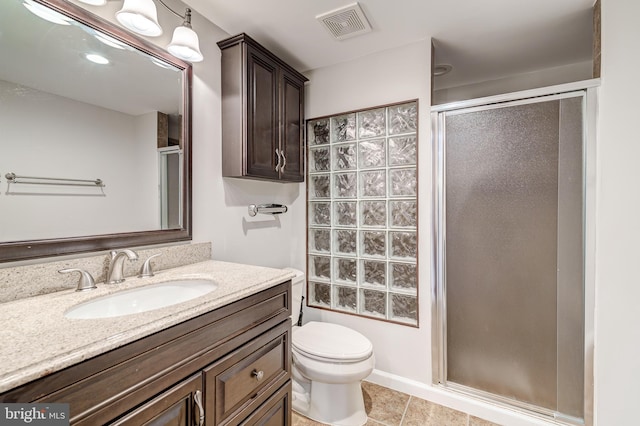 bathroom featuring vanity, tile patterned flooring, a shower with door, and toilet