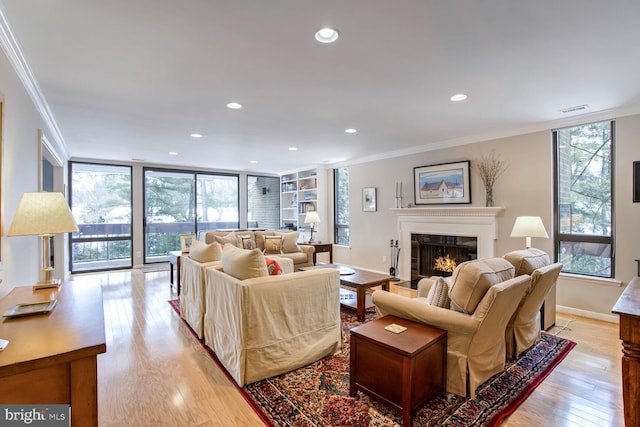 living room featuring ornamental molding, a healthy amount of sunlight, and light wood-type flooring