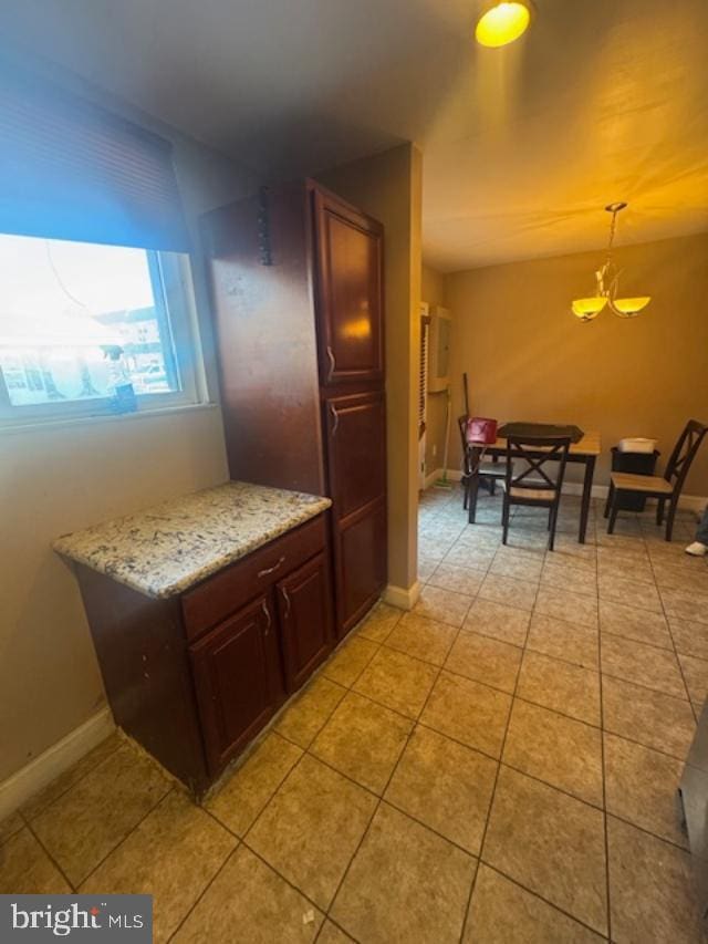 kitchen featuring light tile patterned flooring, pendant lighting, and light stone counters