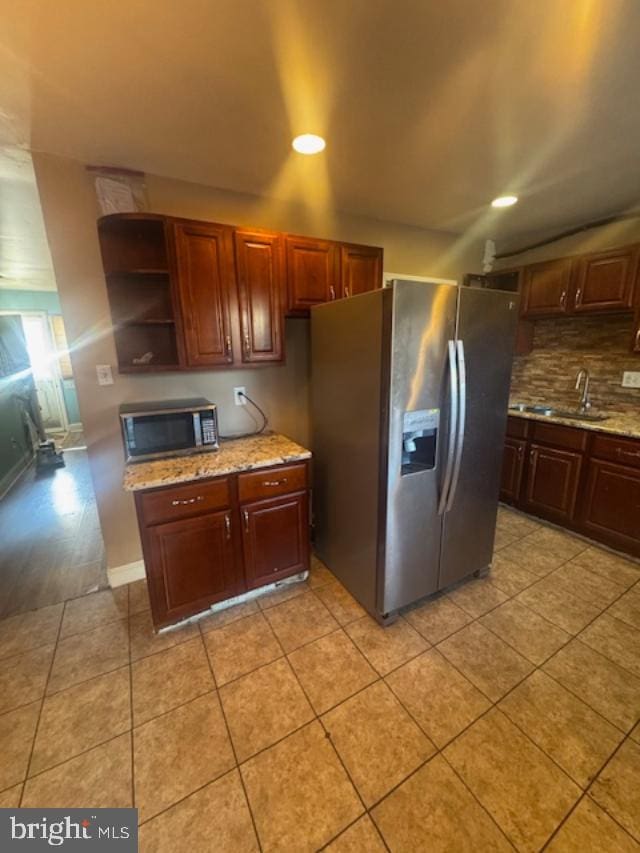 kitchen featuring sink, light tile patterned floors, backsplash, stainless steel appliances, and light stone counters